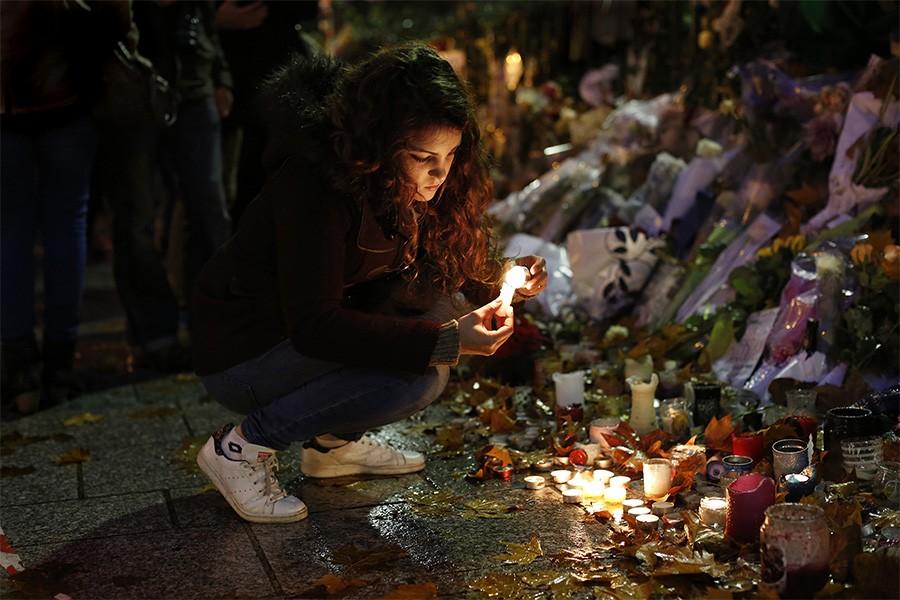 One week after the fatal terrorist attack at the Bataclan Theater, Laura Cappia lights candles in remembrance of the 89 people who died on Nov. 20, 2015 in Paris. Laura was at a nearby bar when the shooting occurred. (Carolyn Cole/Los Angeles Times/TNS)