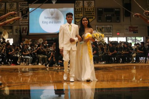 Homecoming King Aaron Velasco and Queen Maya Pegarido walk together as the school cheers. 