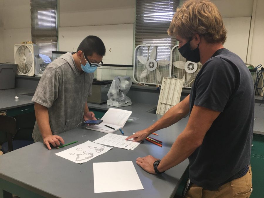 Brian Govier assists Junior Lyu Wei Chen with Pangaea worksheet in Marine Science class.