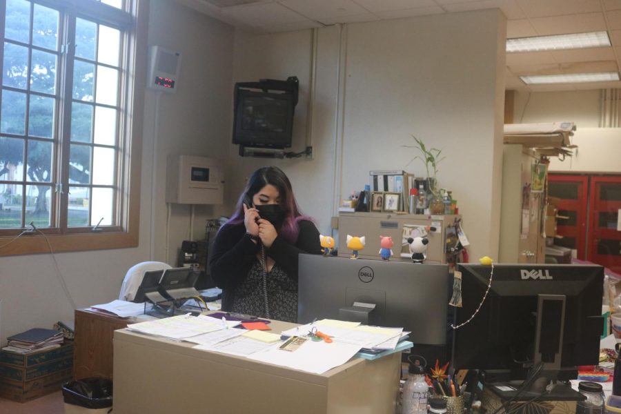 Office assistant Hailey Tanaka is taking a phone call during the morning bustle. 