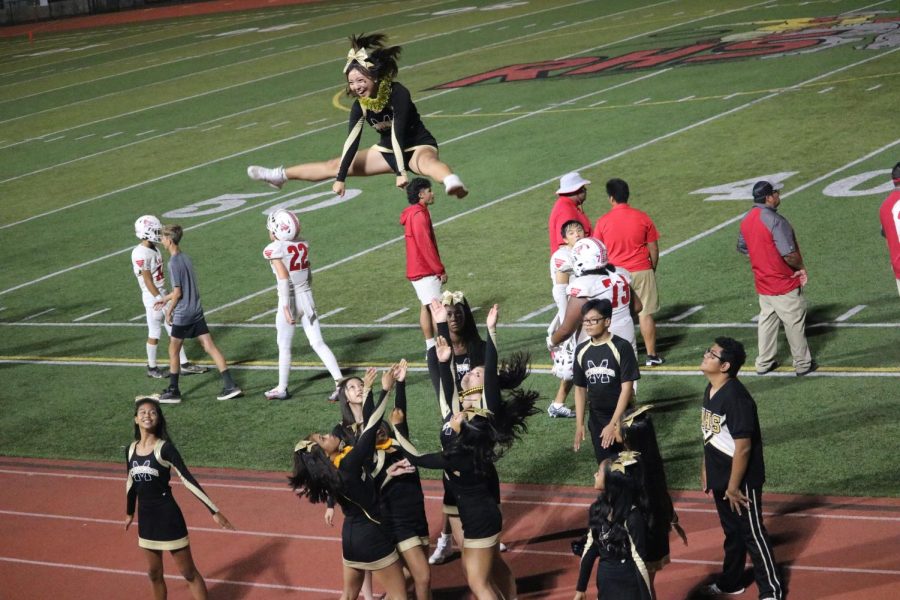 Senior cheerleader Taylor Nakashima is lifted into the air to cheer on and McKinleys football team in their game against Kalani.
