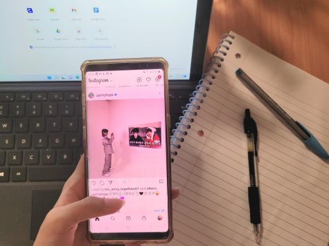 Someone holding a phone on Instagram while doing work