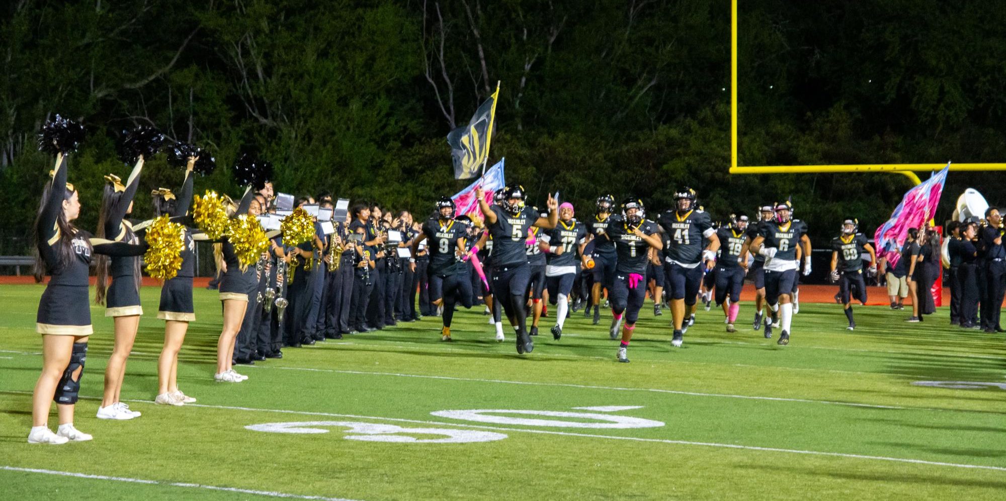 McKinley football team bursts through the breakaway banner after halftime as the Marching Band plays “Gonna Fly Now” from Rocky. 
