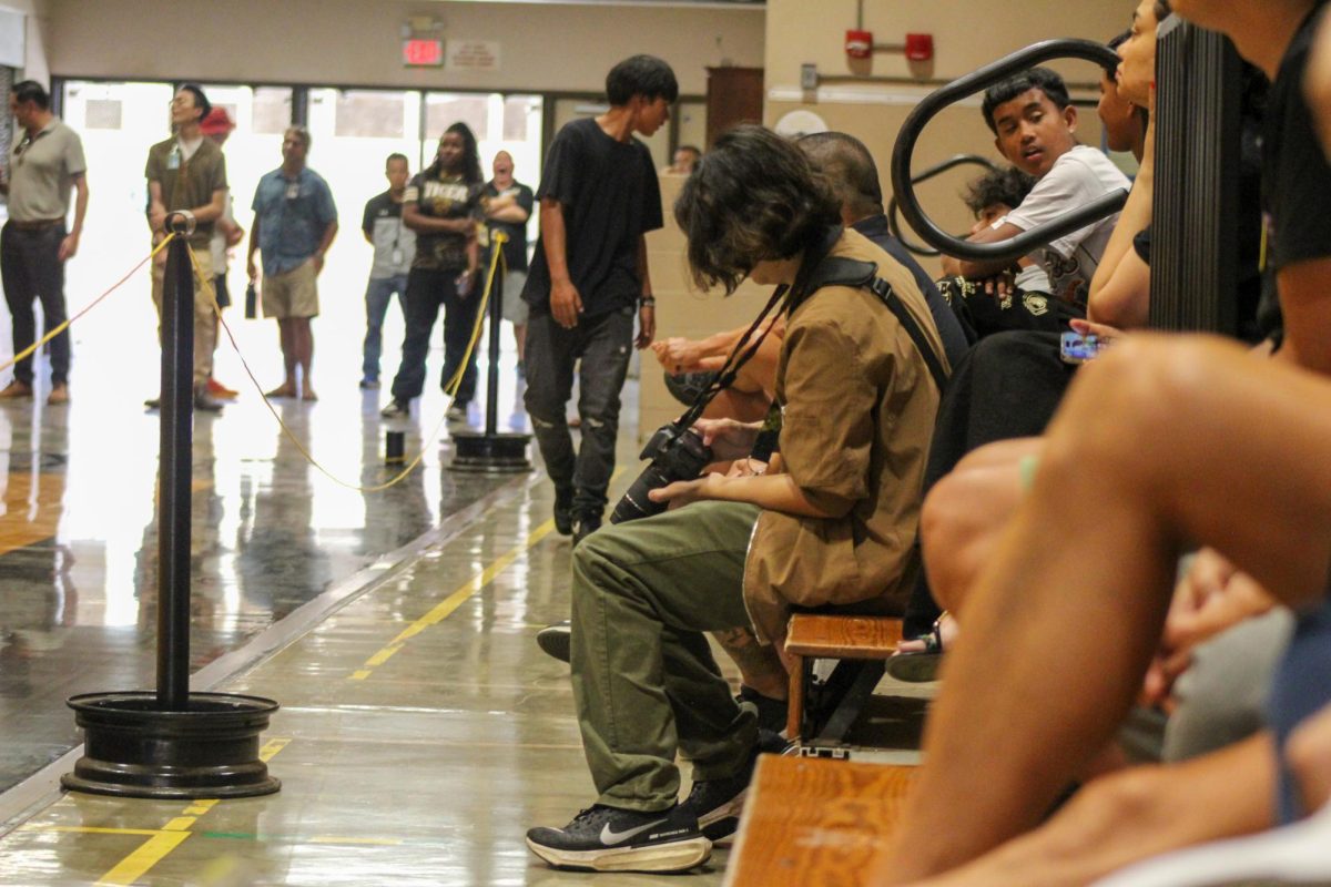 Dominic Niyo looks through his photographs during the Welcome Back Assembly. Photo by Alex Tijerina (c/o '26) 