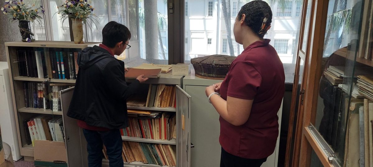 Shane Kaneshiro (c/o ‘24) alongside Taylor Smith, the Pacific Historic Parks’ Programs and Collections Coordinator, in 2025 retrieve some of The Pinion editions held in the library. Kaneshiro's digitization project prioritizes the years 1934–1946, which capture student life before, during and after World War II. Photo by Cynthia Reves.